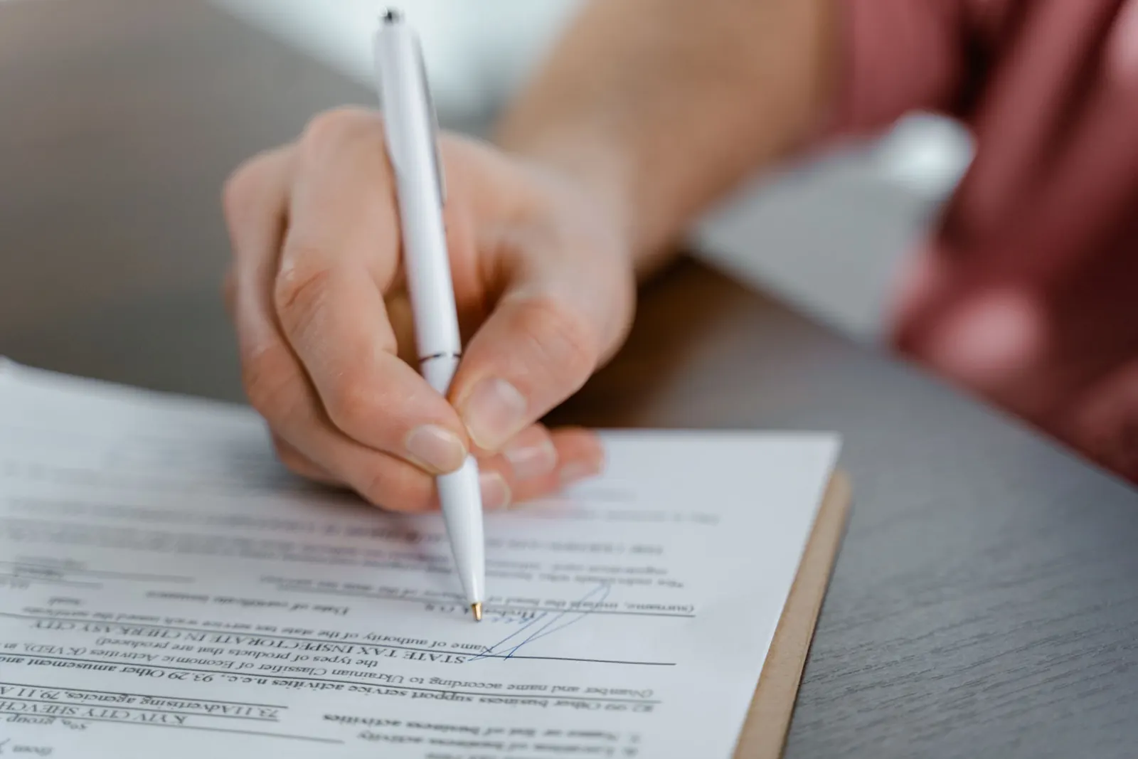Hand signing a document with a white pen