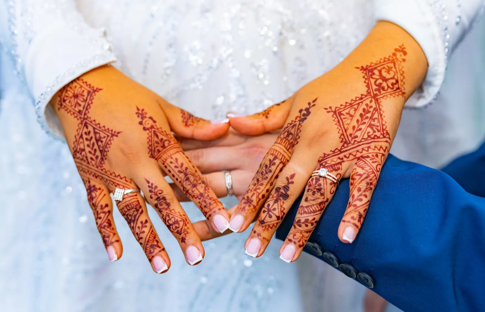 Henna-decorated hands of a bride and groom with wedding rings