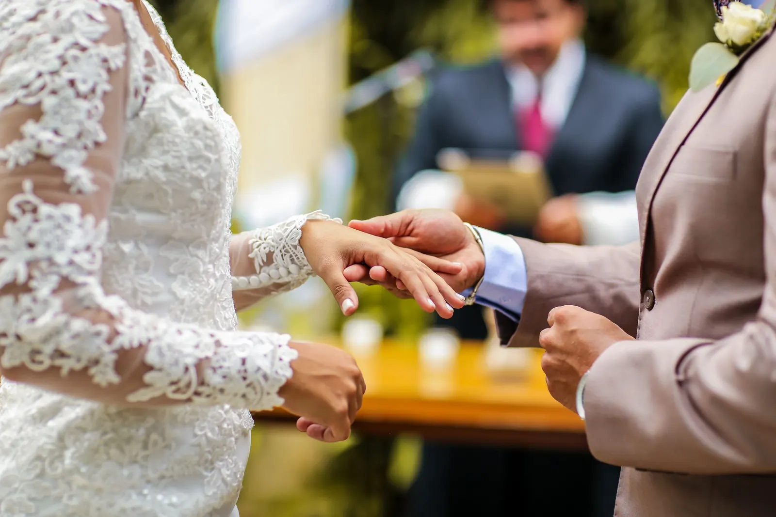 Groom holding the bride's hand at a small outdoor ceremony