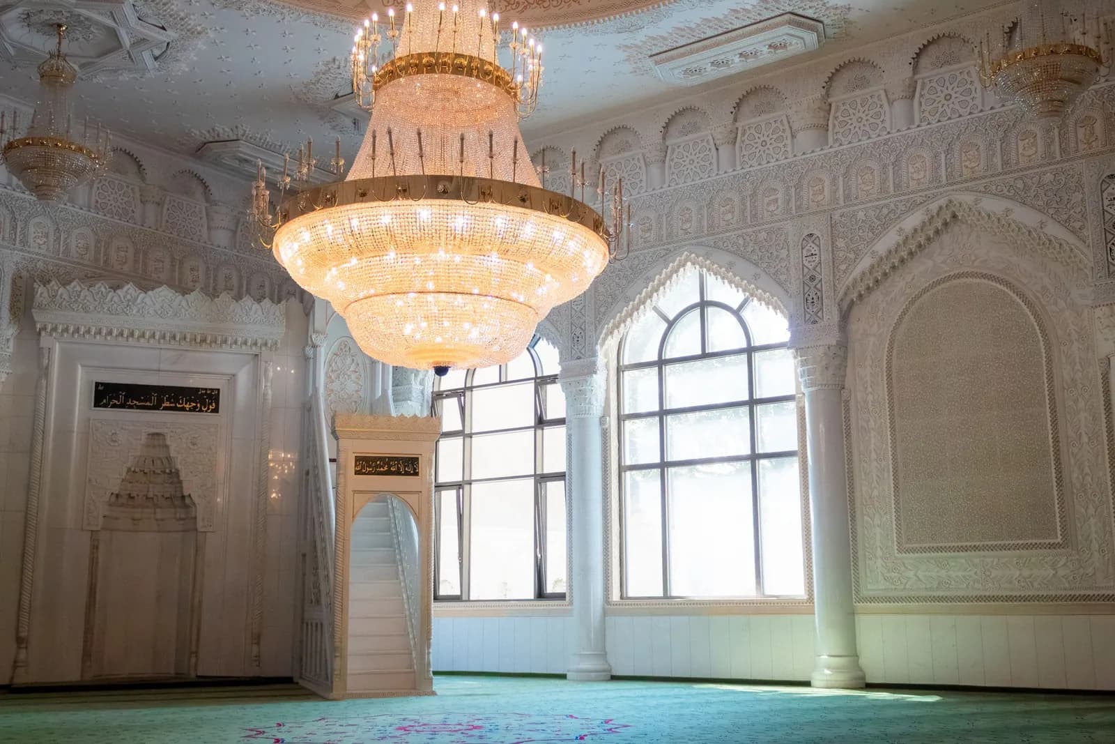 Bright mosque interior with chandelier and arched windows