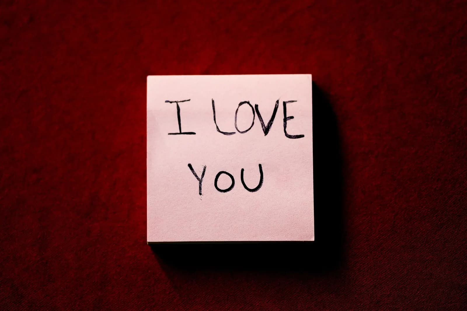 A handwritten note card with a loving message on a red background.