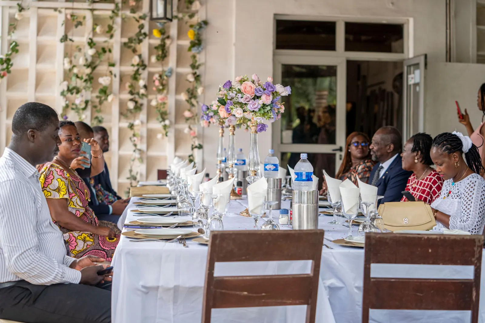 A group of adults gathered around a table at an outdoor celebration.