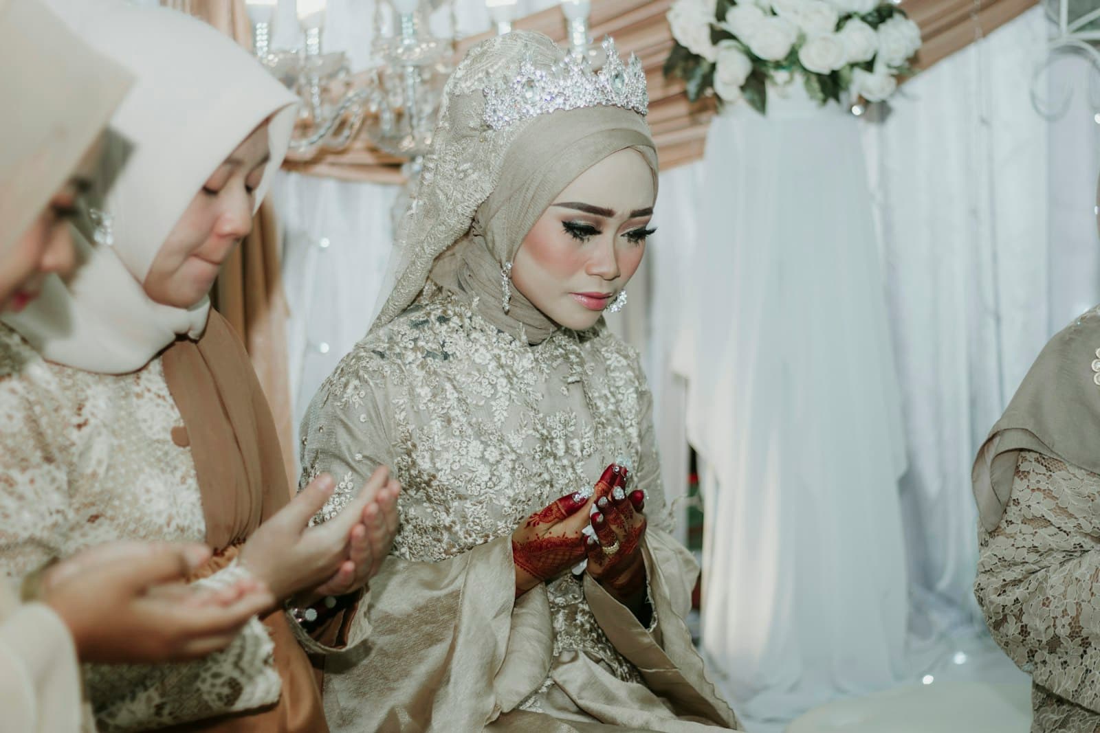 A bride in a white hijab praying with her family before her nikah