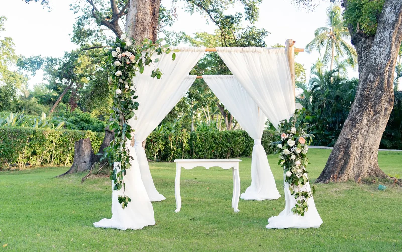 A wedding arch decorated with flowers in a garden setting.