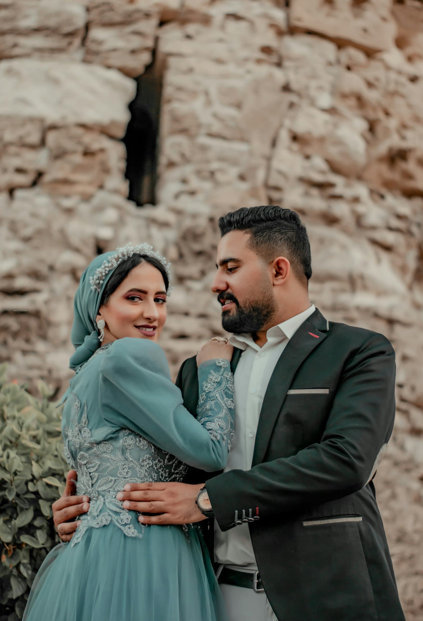 A couple embracing outdoors, the bride in a hijab and the groom in a suit