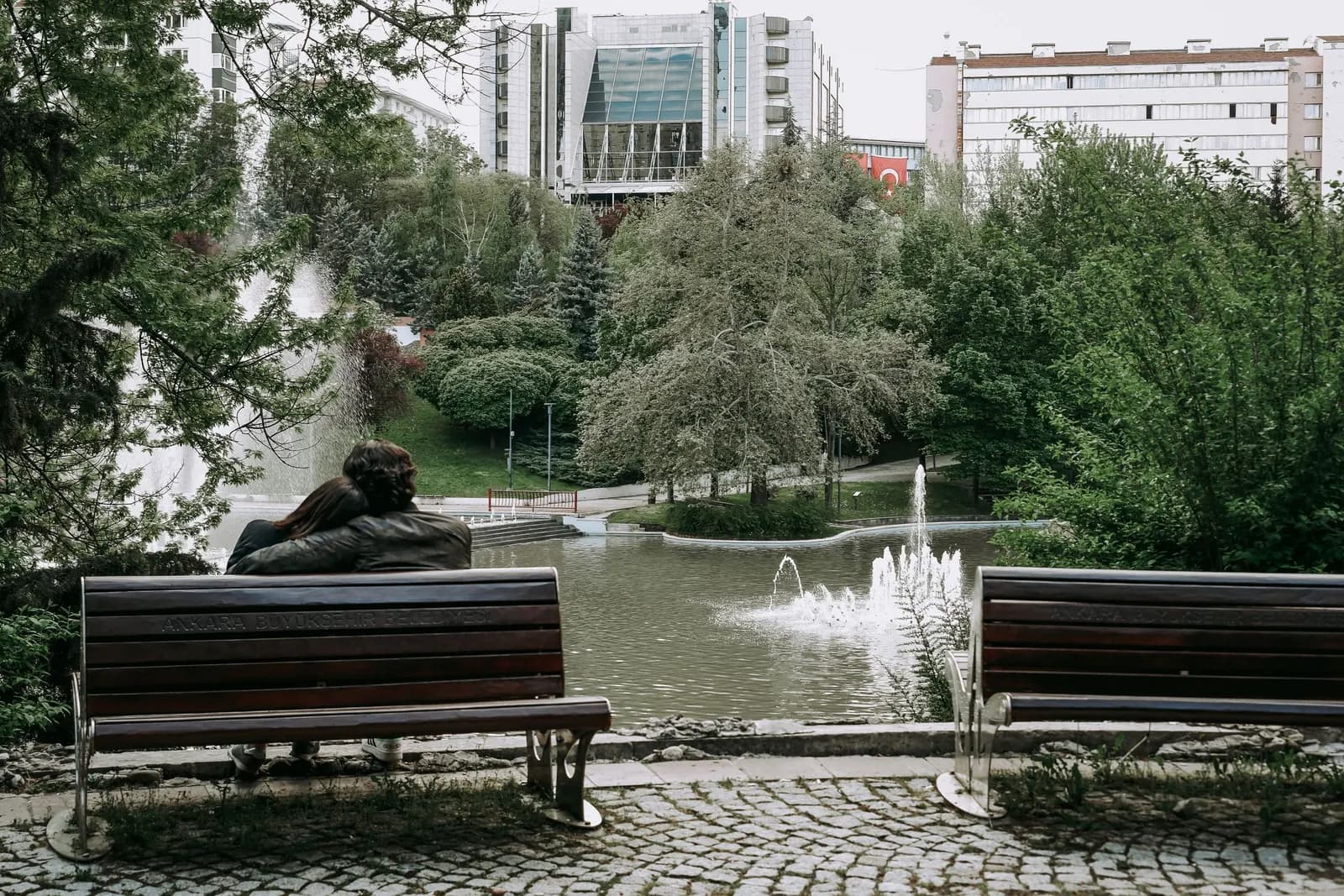 Couple seated on a park bench by a pond