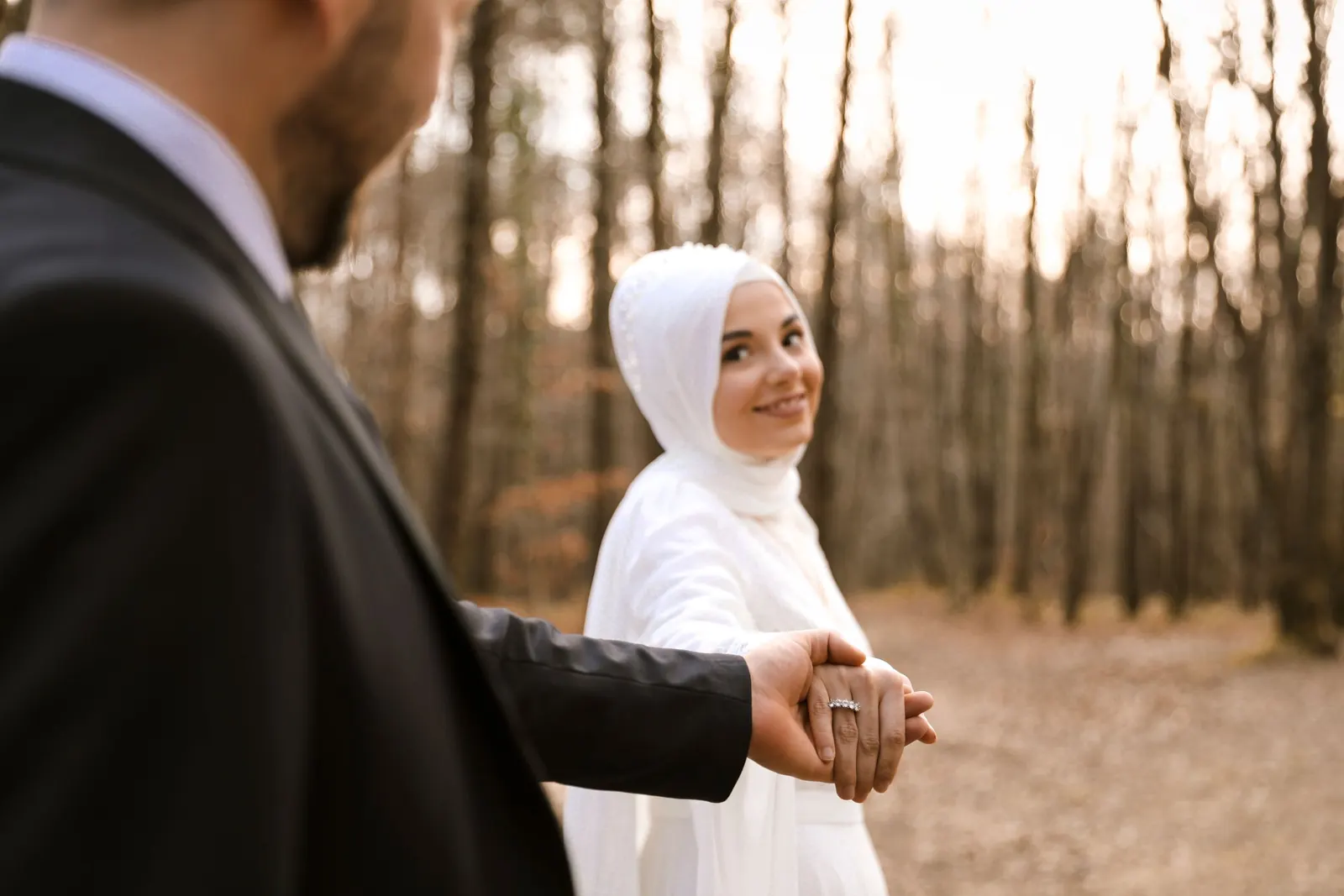 Groom leading his bride by the hand through a wood