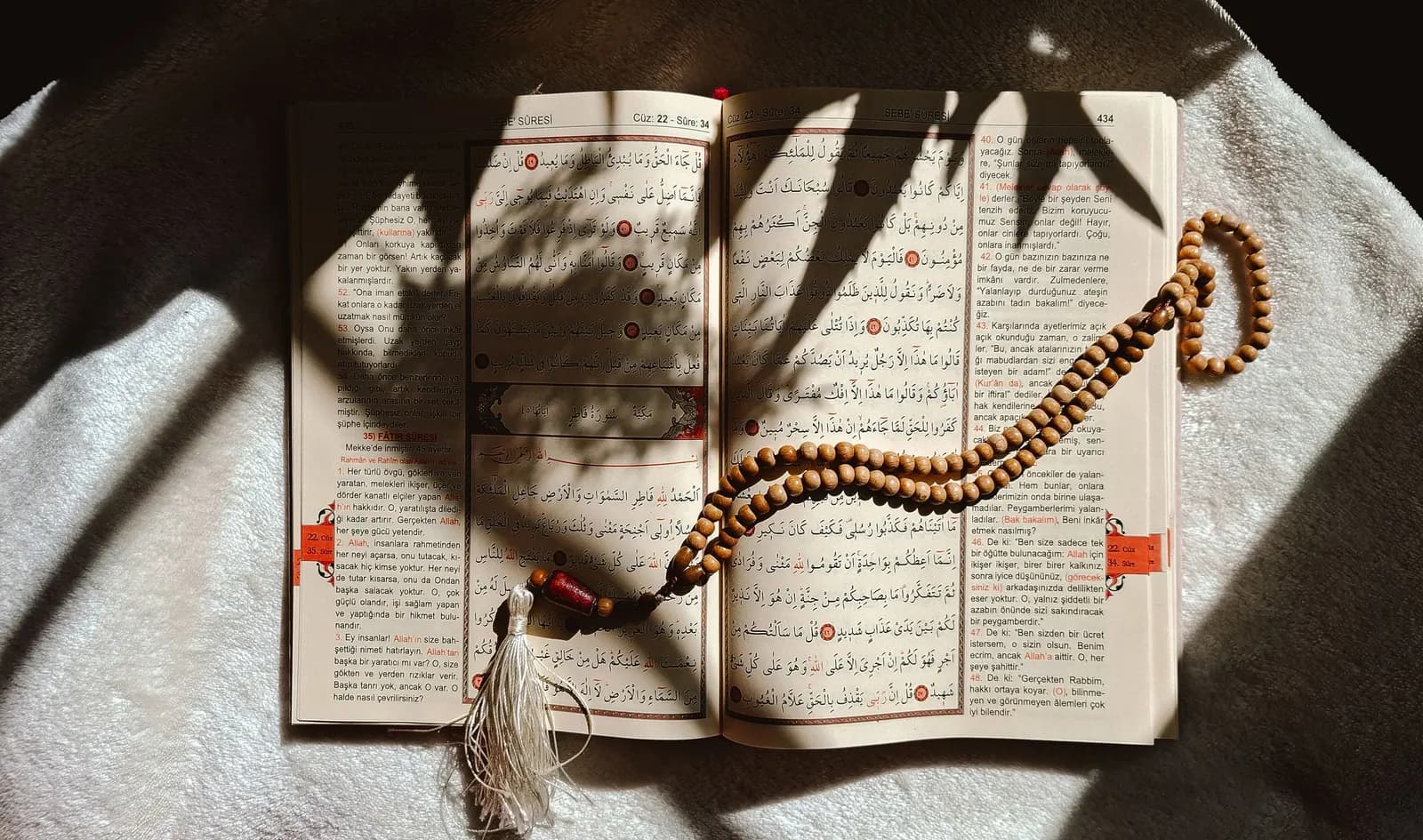 Open Quran with prayer beads in sunlight