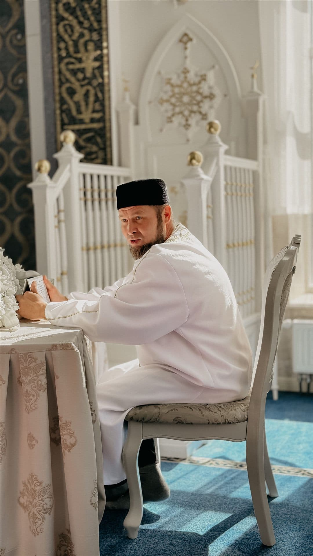 An imam leading a nikah ceremony at a table with the couple's families
